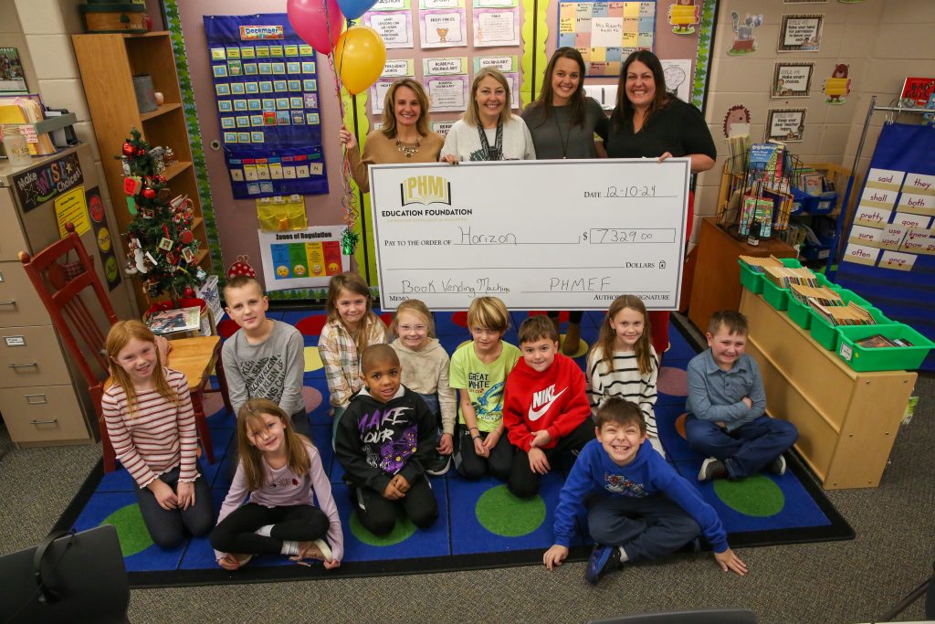 Staff and teachers pose with giant check