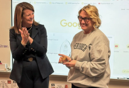 two women smiling, one clapping, the other one holding an award