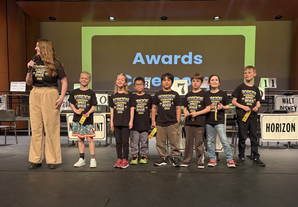 Children standing on stage in front of podiums at an awards ceremony.