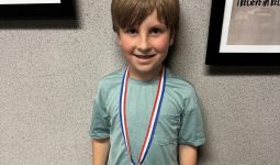 Young boy wearing a medal around his neck.