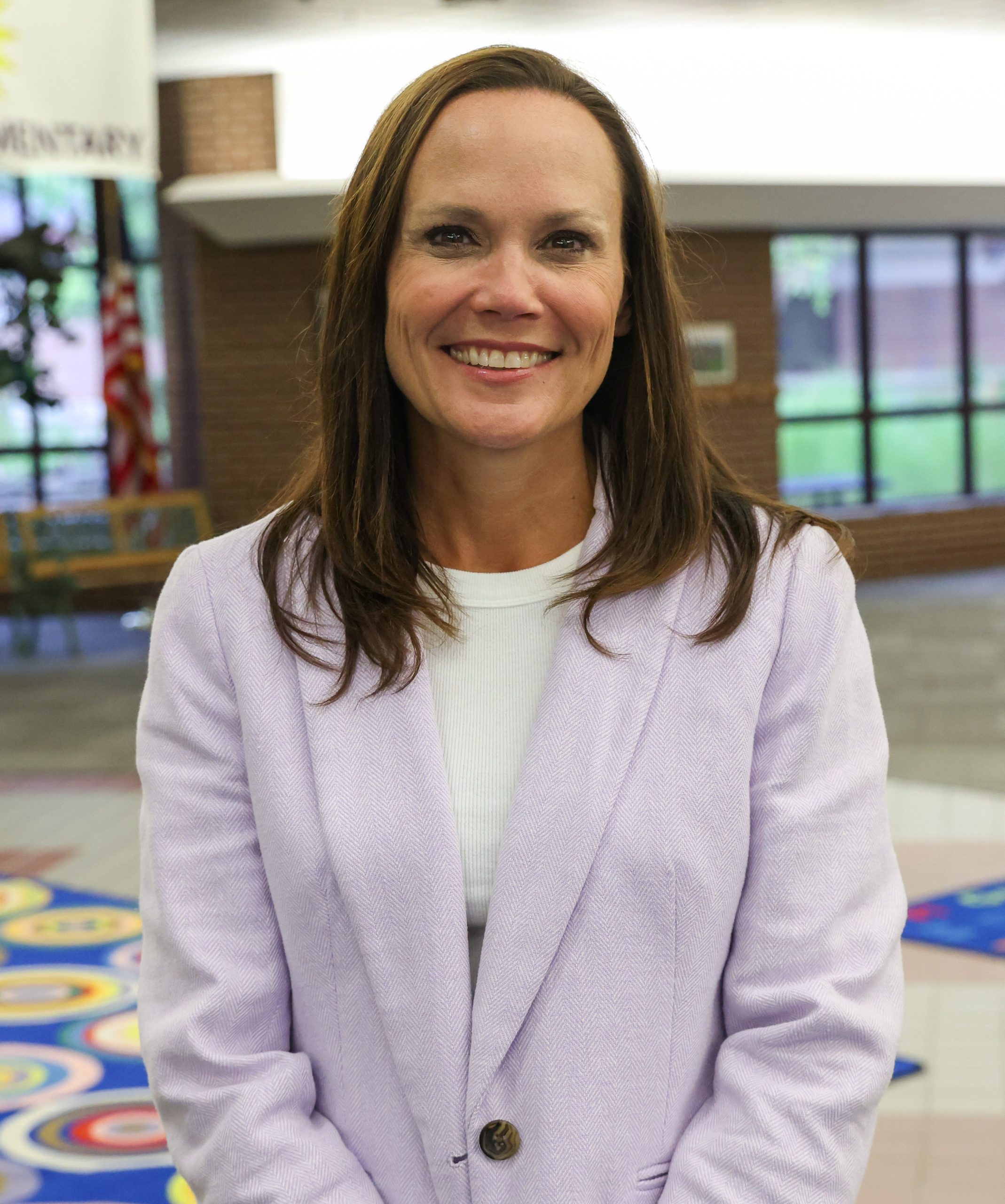 Woman standing in front of building, smiling at camera.