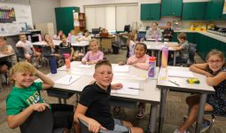 A group of students sitting at desks in a classroom, engaged in an activity