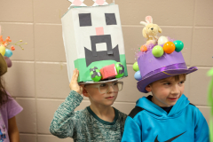 Children in colorful hats they made posing for a picture.