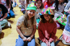 Children in colorful hats they made posing for a picture.